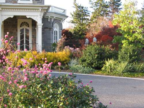 A charming house surrounded by colorful flowers and lush greenery in a serene garden setting.