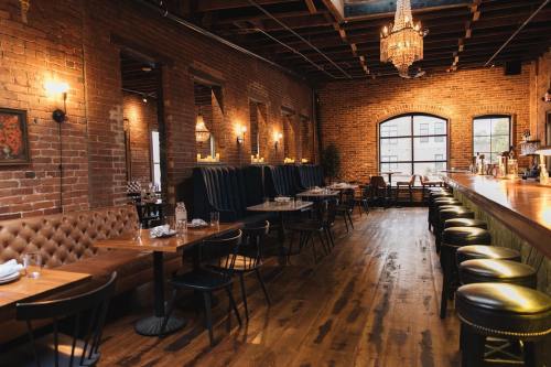 Cozy restaurant interior with exposed brick walls, wooden floors, and elegant lighting, featuring booths and a bar.