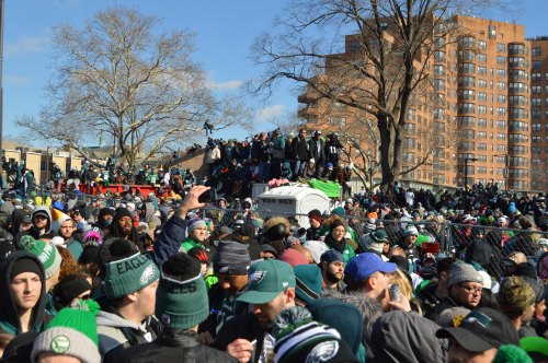 A large crowd of Philadelphia Eagles fans celebrating outdoors, wearing team gear, with buildings in the background.