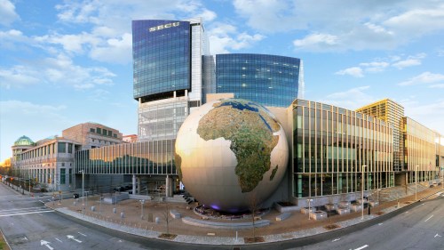 A modern building with a large globe sculpture of Africa in front, set against a clear sky.