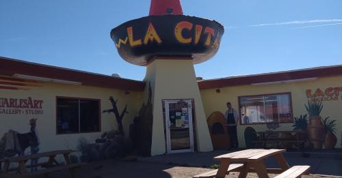 Colorful building with a large sombrero sign reading "La Cita," featuring murals and outdoor seating.