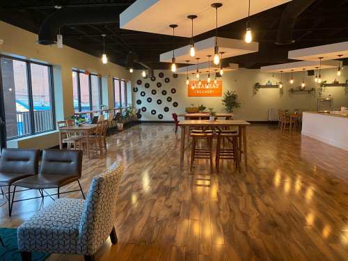 Bright, modern ice cream shop interior with wooden floors, seating areas, and large windows.