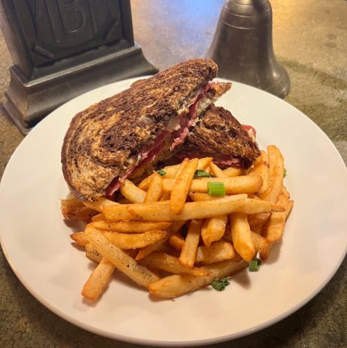 A plate with a toasted sandwich and a side of golden French fries, served on a white dish.