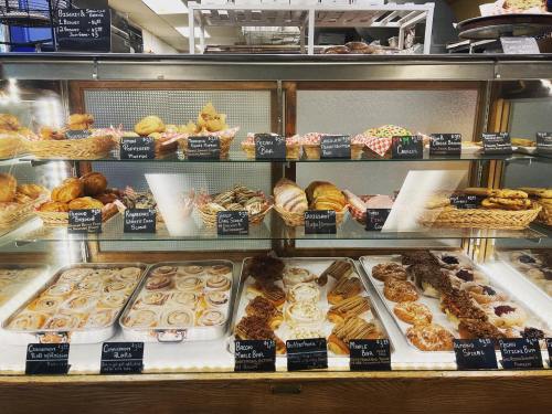 A display case filled with various baked goods, including pastries, cookies, and cinnamon rolls, labeled with prices.