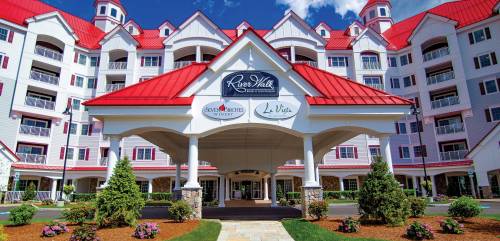 A large building with a red roof and white exterior, featuring a welcoming entrance and landscaped surroundings.