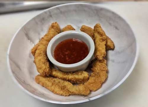 A bowl of crispy fried strips arranged around a small dish of dipping sauce.