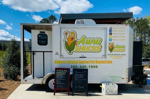A food truck named "Aww Shucks" offering gourmet fire-roasted corn, with a menu board outside.