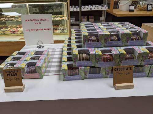 Display of fudge eggs in colorful boxes, with signs for chocolate pecan and a special sale of 30% off.