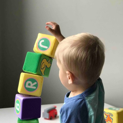 A young child stacking colorful blocks while playing on the floor.
