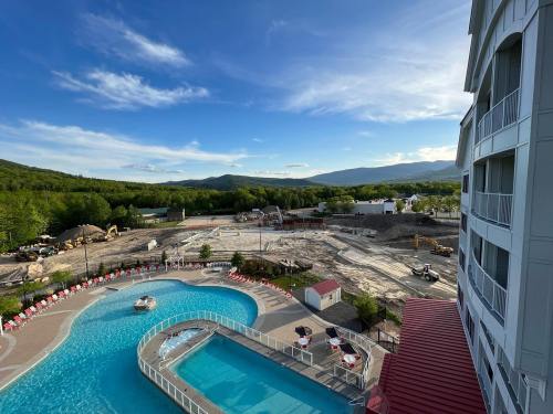 A view of a hotel pool area with a construction site and mountains in the background under a clear blue sky.