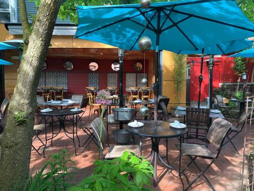 Outdoor dining area with turquoise umbrellas, tables, and greenery, creating a cozy atmosphere.