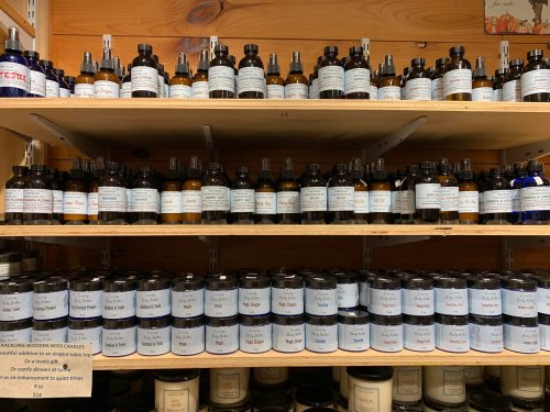 A wooden shelf filled with various bottles of essential oils, each labeled with different names and descriptions.