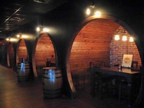 Cozy restaurant interior featuring barrel-shaped booths, wooden walls, and warm lighting.