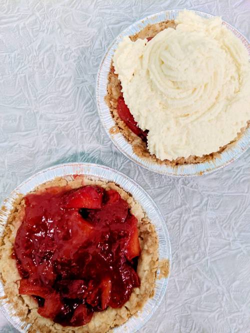 Two small pie crusts: one filled with strawberry filling and the other topped with a fluffy cream layer.