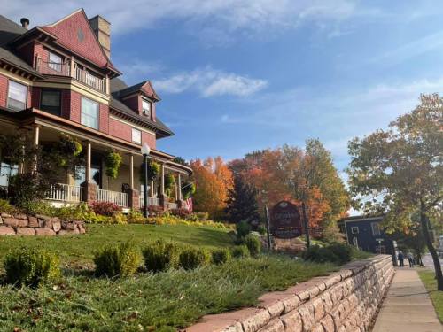 A charming house with a porch, surrounded by colorful autumn trees and a clear blue sky.