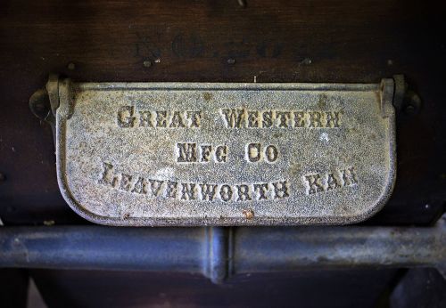 Close-up of a metal plate reading "Great Western Meg Co, Leavenworth Kan" on an antique machine.