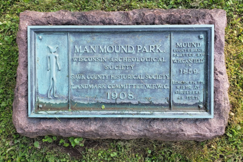 Bronze plaque at Man Mound Park, detailing its historical significance and dimensions, set on a stone base.