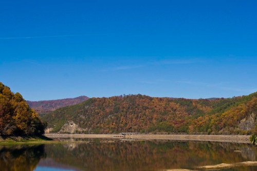 A serene lake surrounded by colorful autumn foliage under a clear blue sky.