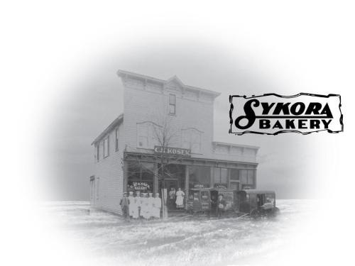 Historic black-and-white photo of Sykora Bakery, featuring a two-story building and people in front.