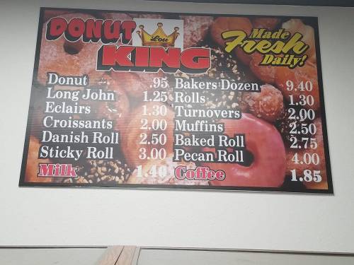 Menu board for Donut King featuring prices for various donuts, pastries, milk, and coffee. Freshly made daily.