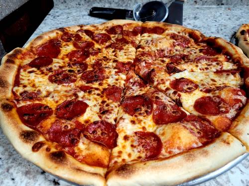 A freshly baked pepperoni pizza with melted cheese and a golden crust, sliced into eight pieces.