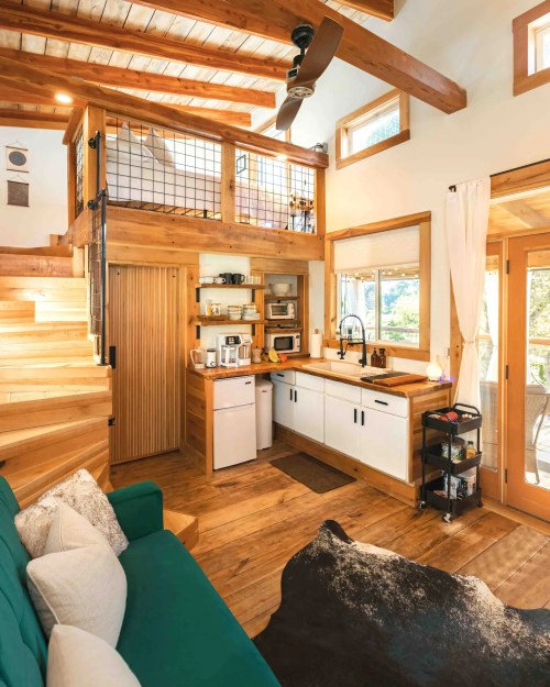 Cozy interior of a small home featuring a kitchen, living area, and lofted space with wooden accents and natural light.