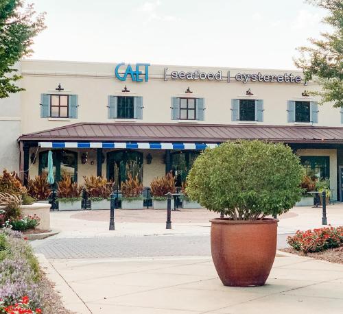 Exterior of a seafood restaurant named "CAET" with a landscaped entrance and potted plant in the foreground.