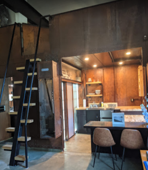 A modern kitchen with wooden accents, a dining table, and a staircase leading to an upper level.