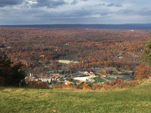 A panoramic view of a valley filled with autumn foliage, showcasing a small town nestled among the trees.