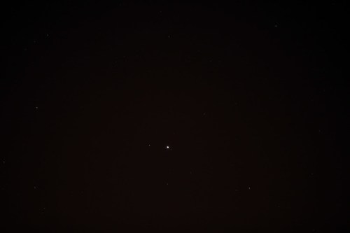 A dark night sky filled with scattered stars, featuring a bright central star.