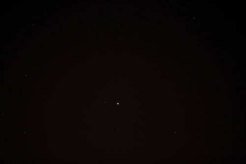 A dark night sky filled with scattered stars, featuring a bright central star.
