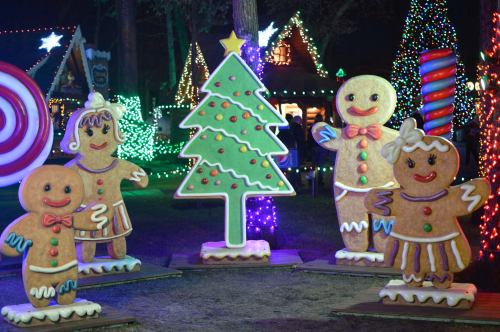 Colorful gingerbread figures and a decorated Christmas tree surrounded by festive lights in a holiday display.