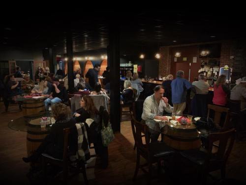 A lively bar scene with patrons seated at tables, enjoying drinks and conversation in a warm, inviting atmosphere.