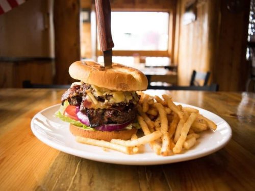 A juicy burger with lettuce, tomato, and cheese, served with a side of crispy fries on a wooden table.
