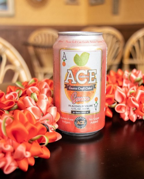 A can of Ace Guava Craft Cider on a table, surrounded by vibrant orange flowers.