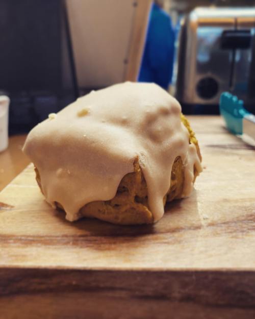 A freshly baked pastry with a glossy icing, resting on a wooden surface.