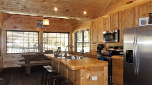 Cozy wooden kitchen with a large island, stainless steel appliances, and a dining area with a rustic table.