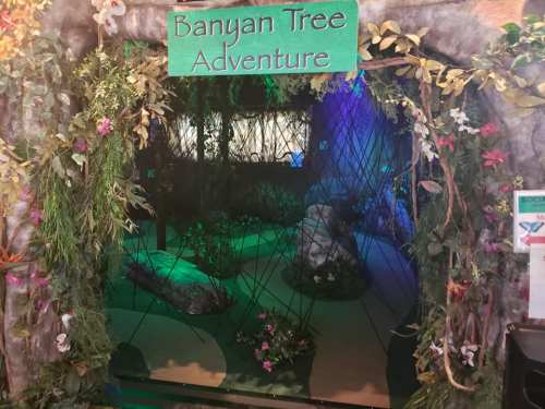 Entrance to the "Banyan Tree Adventure," featuring lush greenery and colorful lighting.