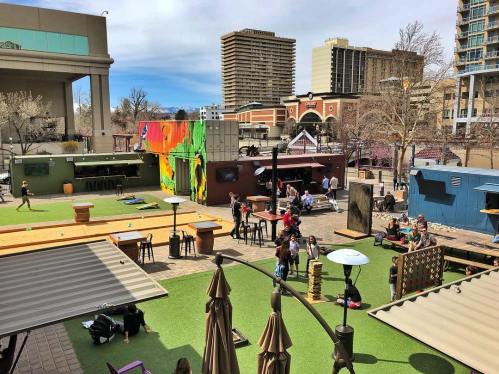 A vibrant outdoor space with colorful murals, seating areas, and people enjoying games and socializing.