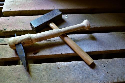 A wooden mallet and a caliper resting on a rustic wooden surface.