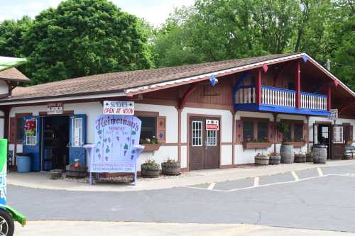 A charming, two-story building with a wooden facade, colorful flower pots, and a sign reading "Heitmann's Winery."