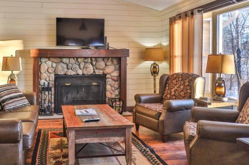 Cozy living room with a stone fireplace, two armchairs, a wooden coffee table, and a TV mounted on the wall.