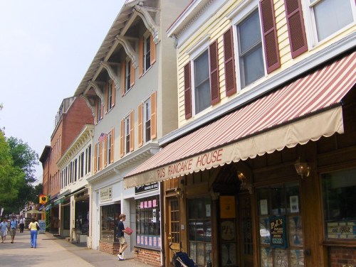 A charming street lined with shops, including a pancake house, featuring colorful buildings and pedestrians strolling.