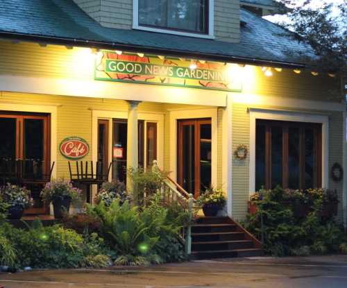 A cozy café entrance with a sign reading "Good News Gardening," surrounded by plants and warm lighting.