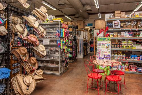 A colorful store interior featuring cowboy hats, various merchandise, and a small table with red chairs.