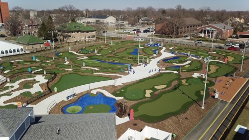 Aerial view of a mini-golf course featuring various holes, water features, and landscaped areas.