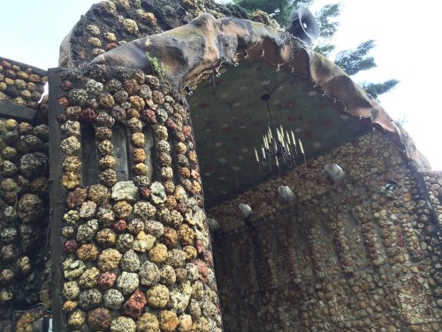 A unique structure made of colorful stones, featuring an arched entrance and a chandelier hanging from the ceiling.
