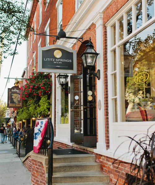 A charming brick building with a sign for Lititz Springs, surrounded by flowers and a welcoming entrance.