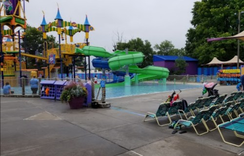 A colorful water park featuring slides, a pool, and lounge chairs under a cloudy sky.