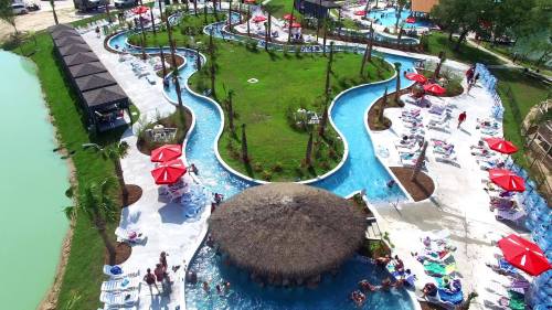 Aerial view of a resort pool area with winding water slides, green lawns, and lounge chairs under red umbrellas.